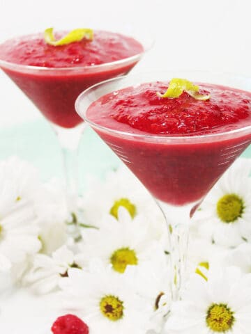 Two rapberry daiquiri drinks among daisies.