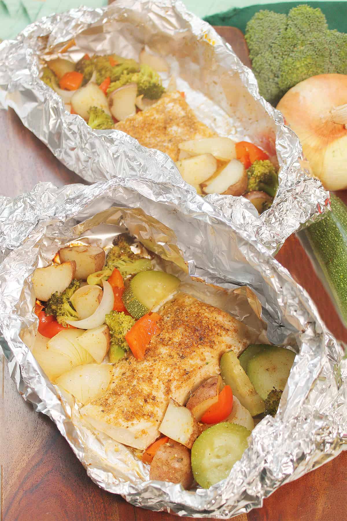 Two open packets of grilled mahi mahi in foil.