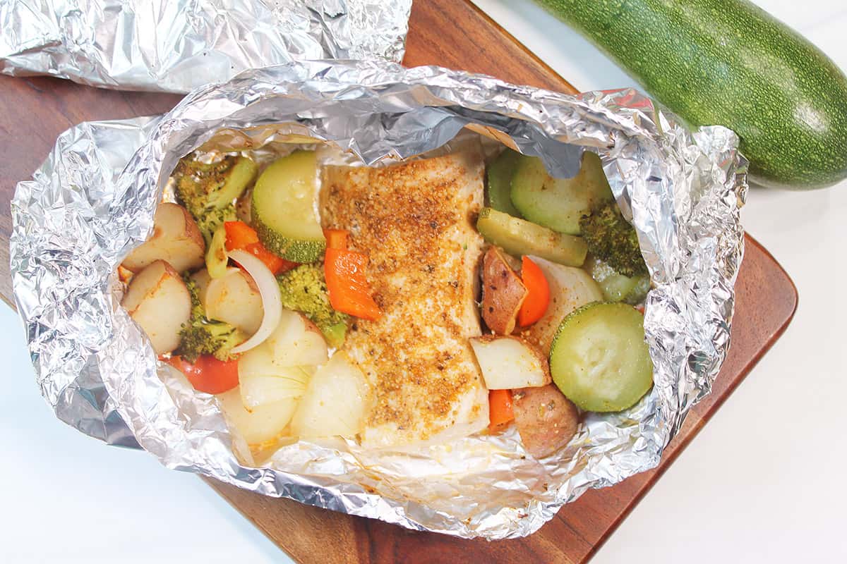 Opened packet of cooked mahi mahi with vegetables.