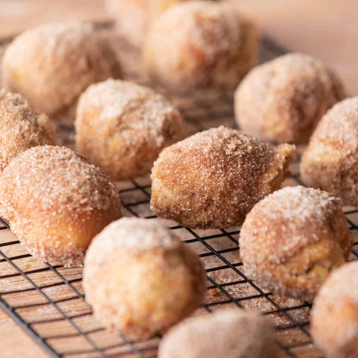 Donut holes covered with cinnamon sugar on wire rack.