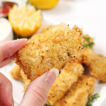 Holding a crispy fish stick over platter.