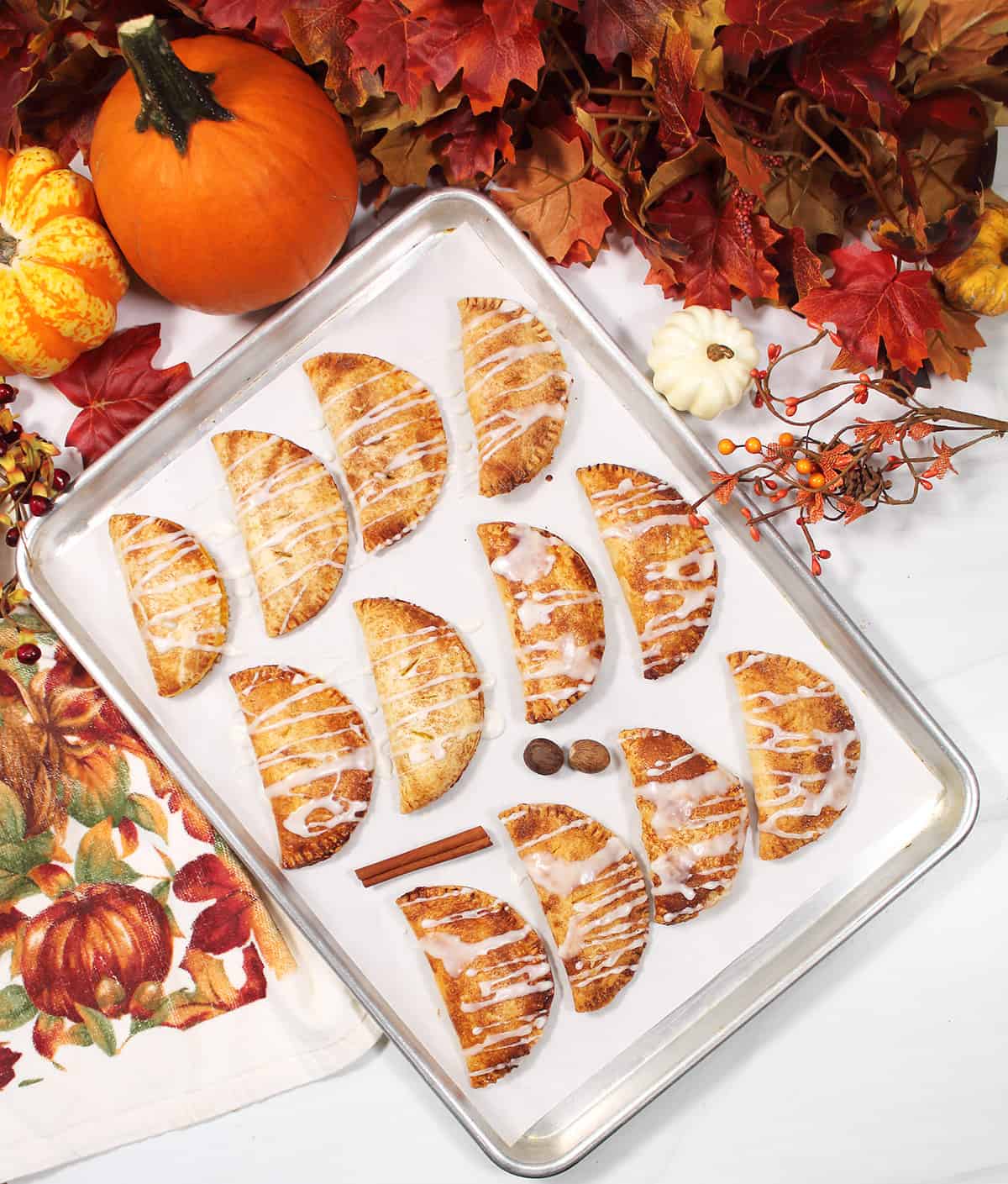 Pumpkin Hand Pies drizzles with vanilla glaze on cookie sheet.