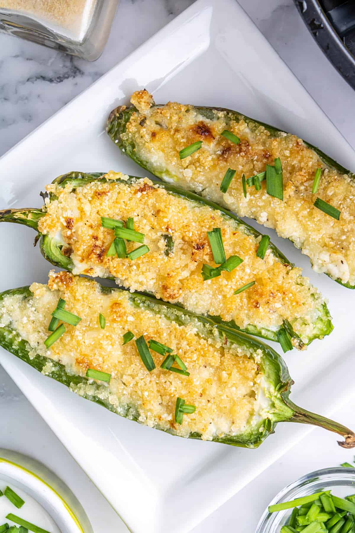 Three stuffed jalapenos on serving plate.