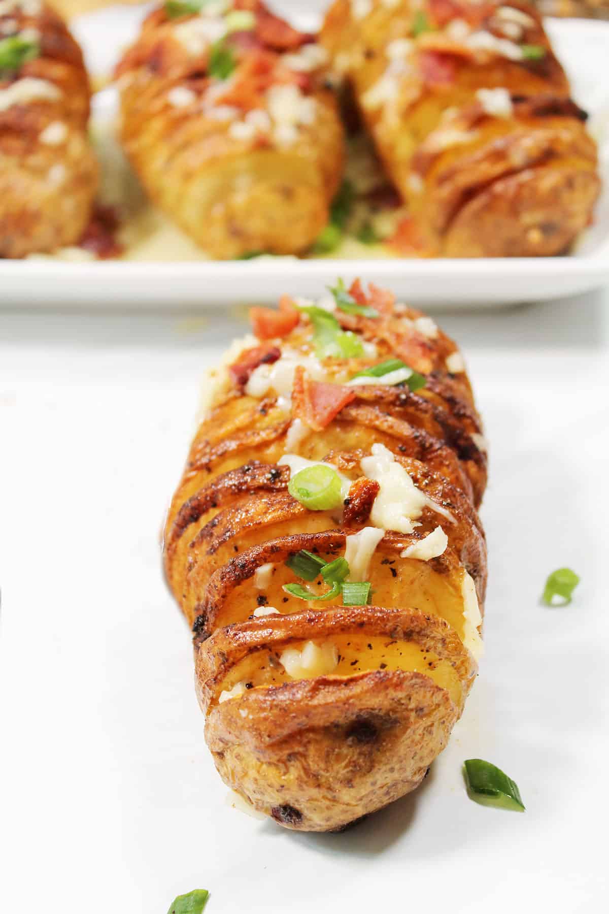 Dressed air fried hasselback potato in front of platter.
