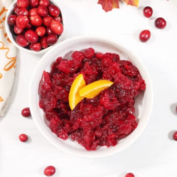 Overhead of orange cranberry sauce with cranberries all around.