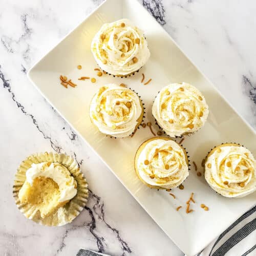 Overhead of cupcakes on platter with halved one in front.