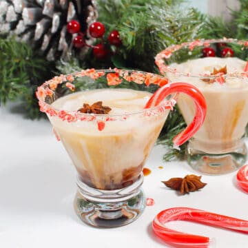Two holiday white russian cocktails by greenery.