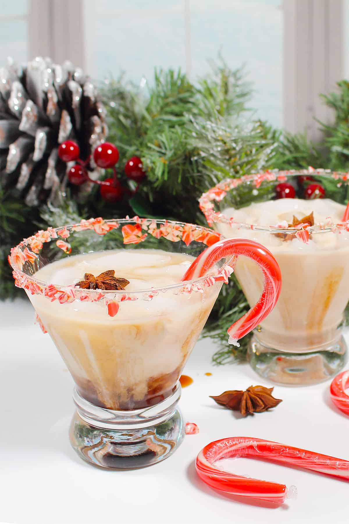 Two peppermint white russian cocktails with candy cane stirrer.