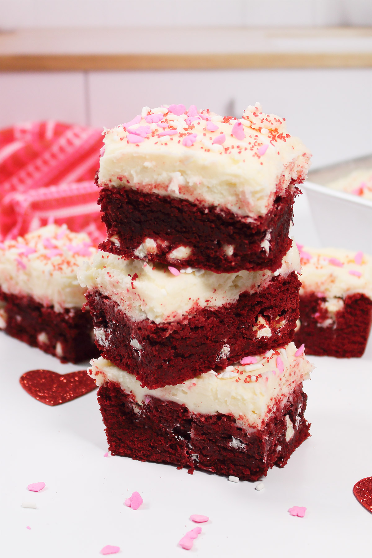 Stack of three red velvet brownies with cream cheese frosting.