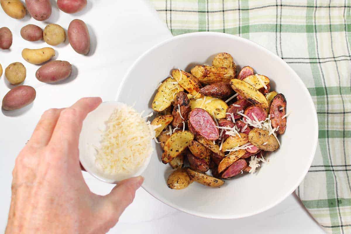 Finishing potatoes with a sprinkling of Parmesan cheese.
