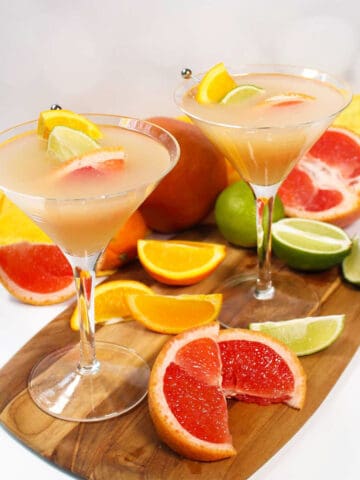 Two grapefruit vodka martinis with sliced fruit.