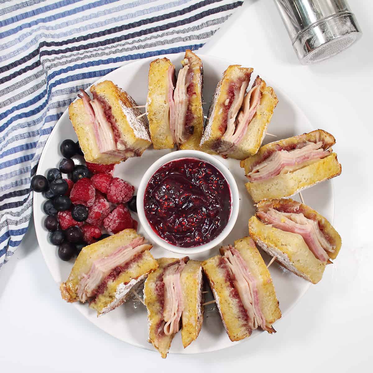 Overhead of quartered sandwiches with fruit and jam.