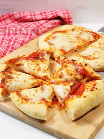 Sliced pizza with red checkered towel.