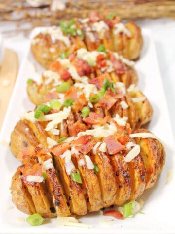 Bacon covered Hasselback potatoes on platter.