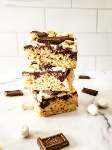 A stack of cut smores rice krispie treats with marshmallows and chocolate bars.