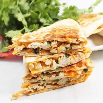 Stack of cut buffalo chicken quesadillas on white table.