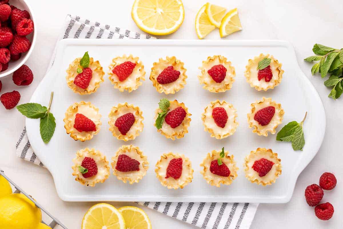 Decorated tarts on white serving board.