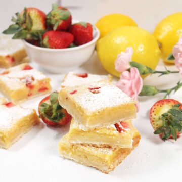 Stack of three lemonade bars among lemons and strawberries.