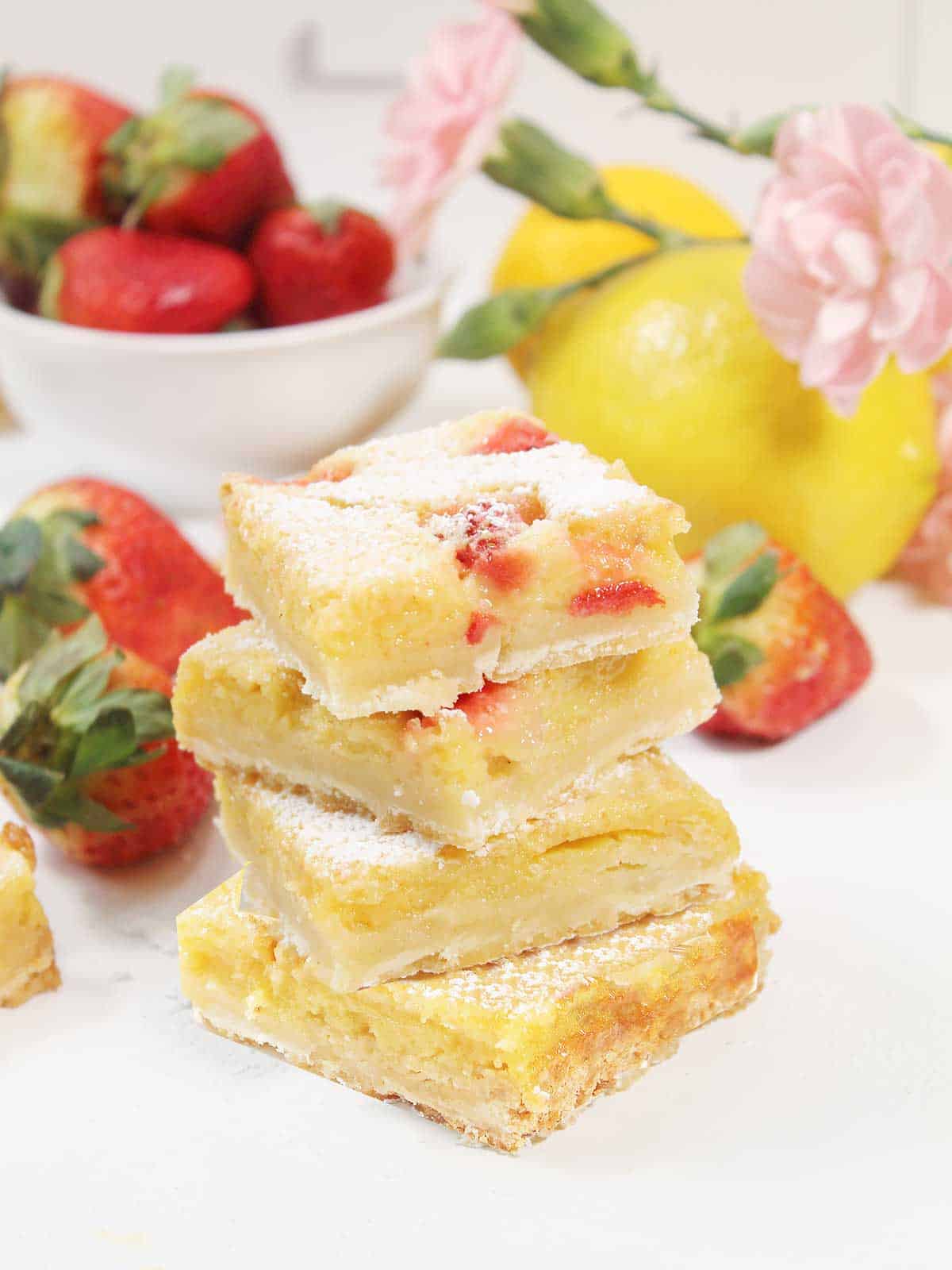 Stack of four lemonade bars with strawberries and lemons.