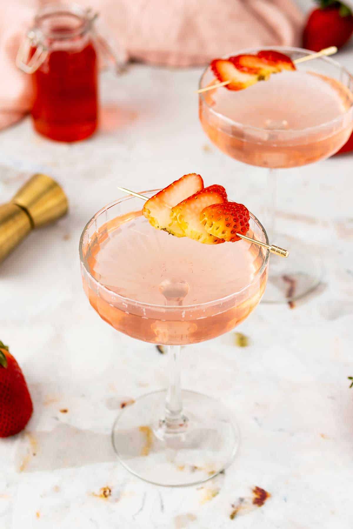 Two martinis with strawberry garnish.