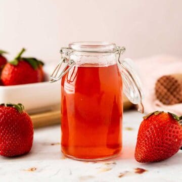 Strawberry syrup in a jar by strawberries and muddler.