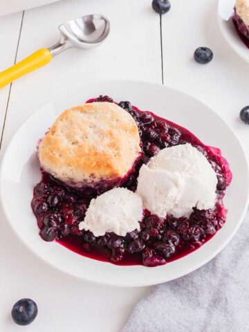 Mixed Berry Cobbler with ice cream on wooden table.