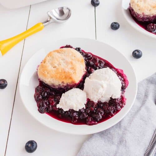 Mixed Berry Cobbler with ice cream on wooden table.