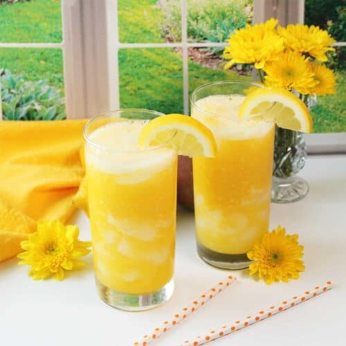 Mango lemonade in glasses with lemon garnish.