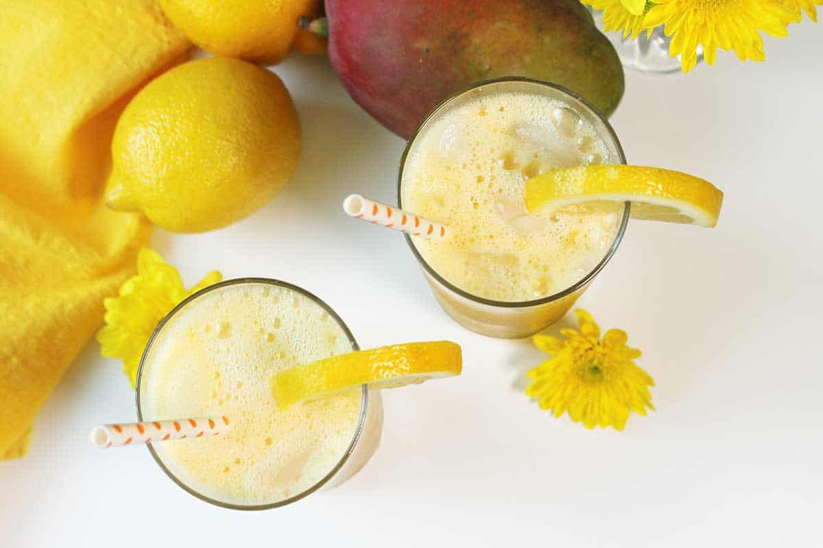 Overhead of two  glasses of frozen mango lemonade showing frothiness.