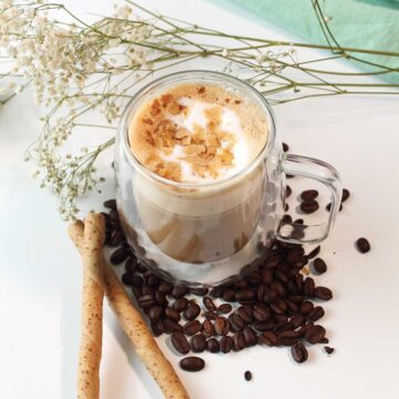 Pistachio latte surrounded by espresso beans.