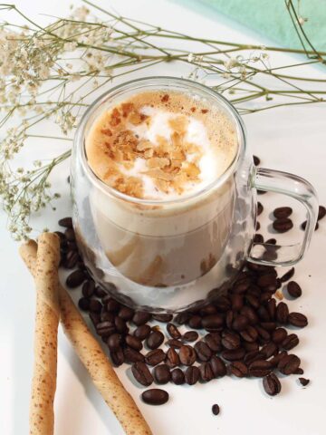 Pistachio latte surrounded by espresso beans.