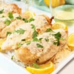 Closeup of chicken with sauce on serving platter.