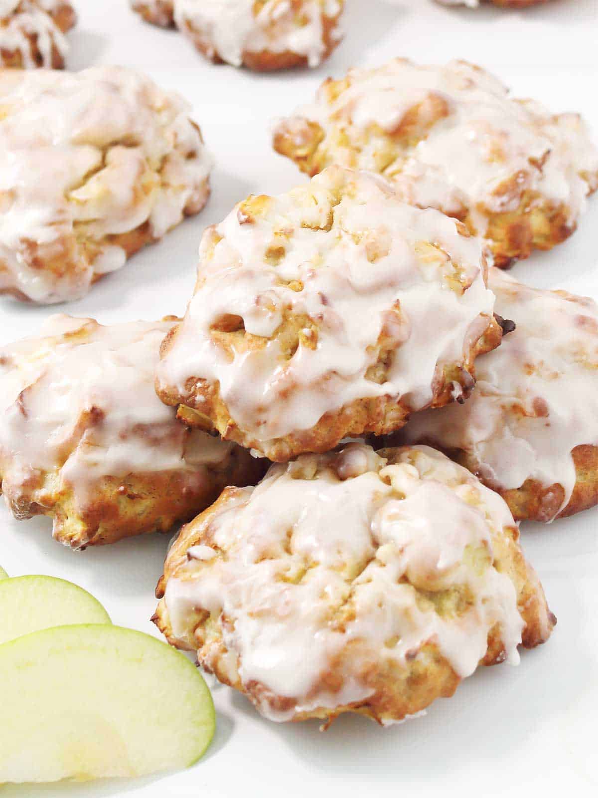 Scattered air fryer apple fritters with glaze on table.