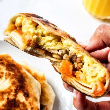 Holding egg tortilla wrap with bite out of it.