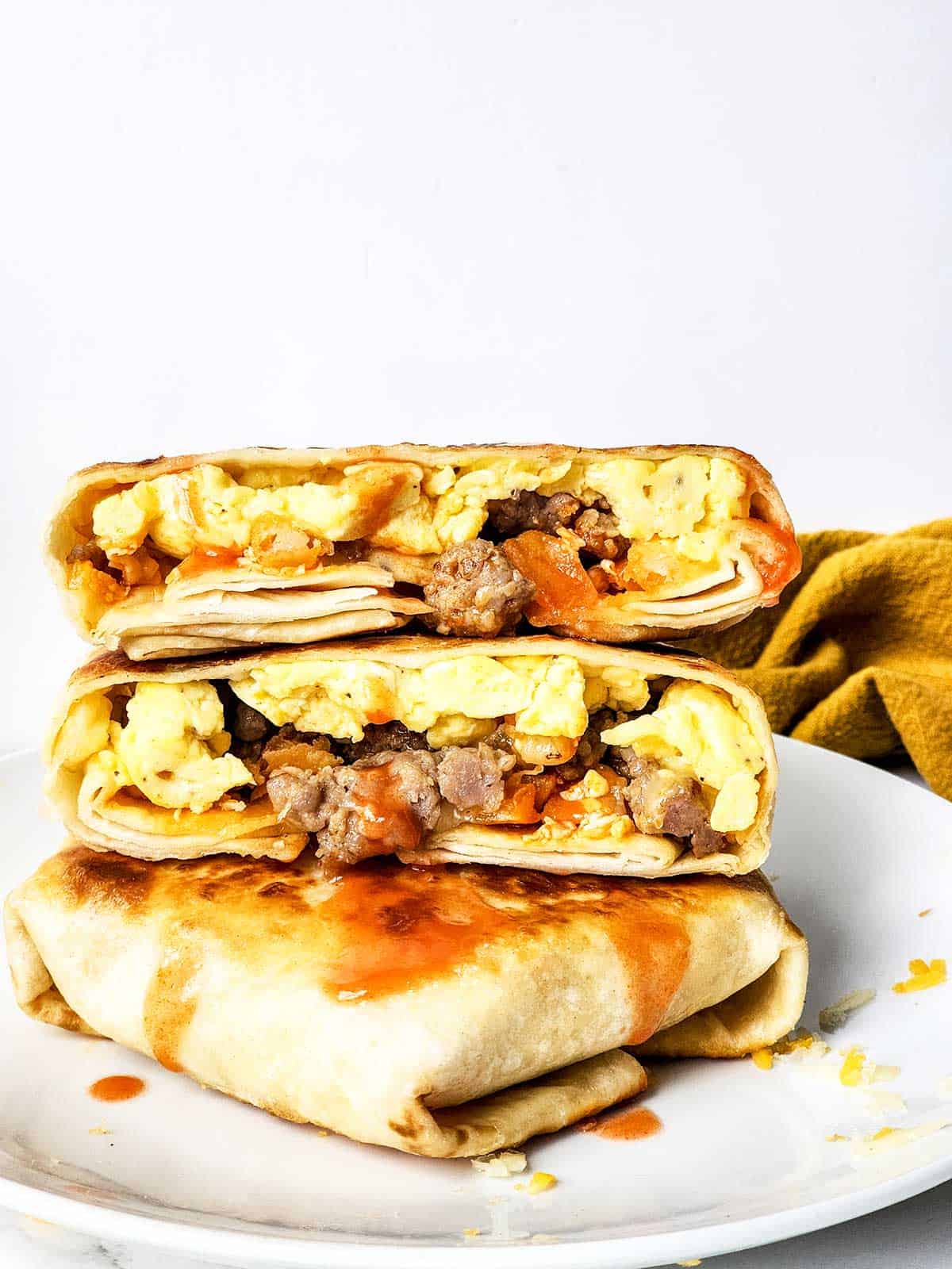 Stacked breakfast crunchwraps with top one cut in half.