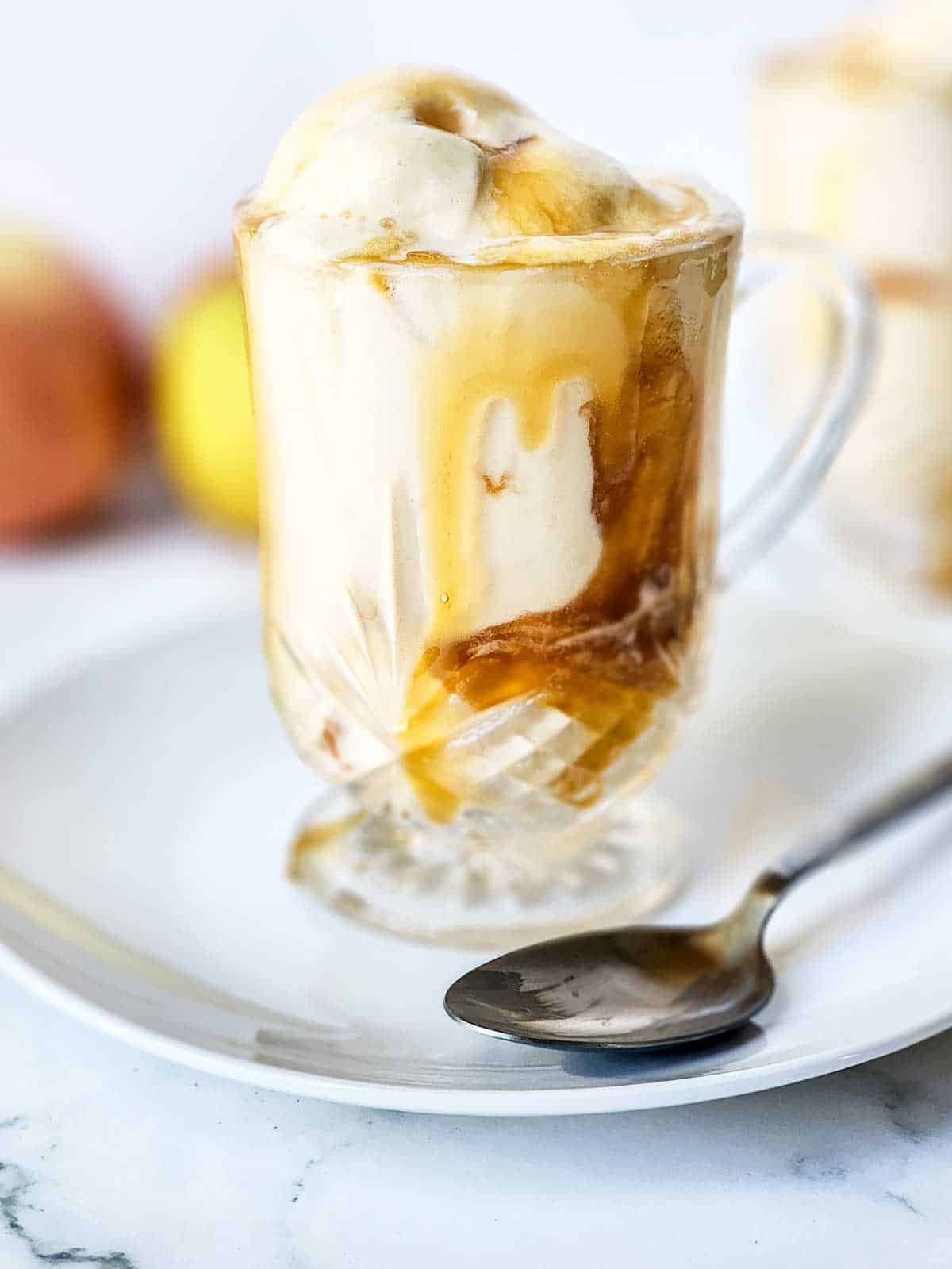 Caramel apple cider float in mug on plate with spoon.