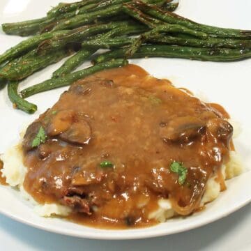 Cube steak plated over potatoes with gravy.
