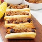 Grilled bratwurst with caramelized onion and fennel relish on wooden board.