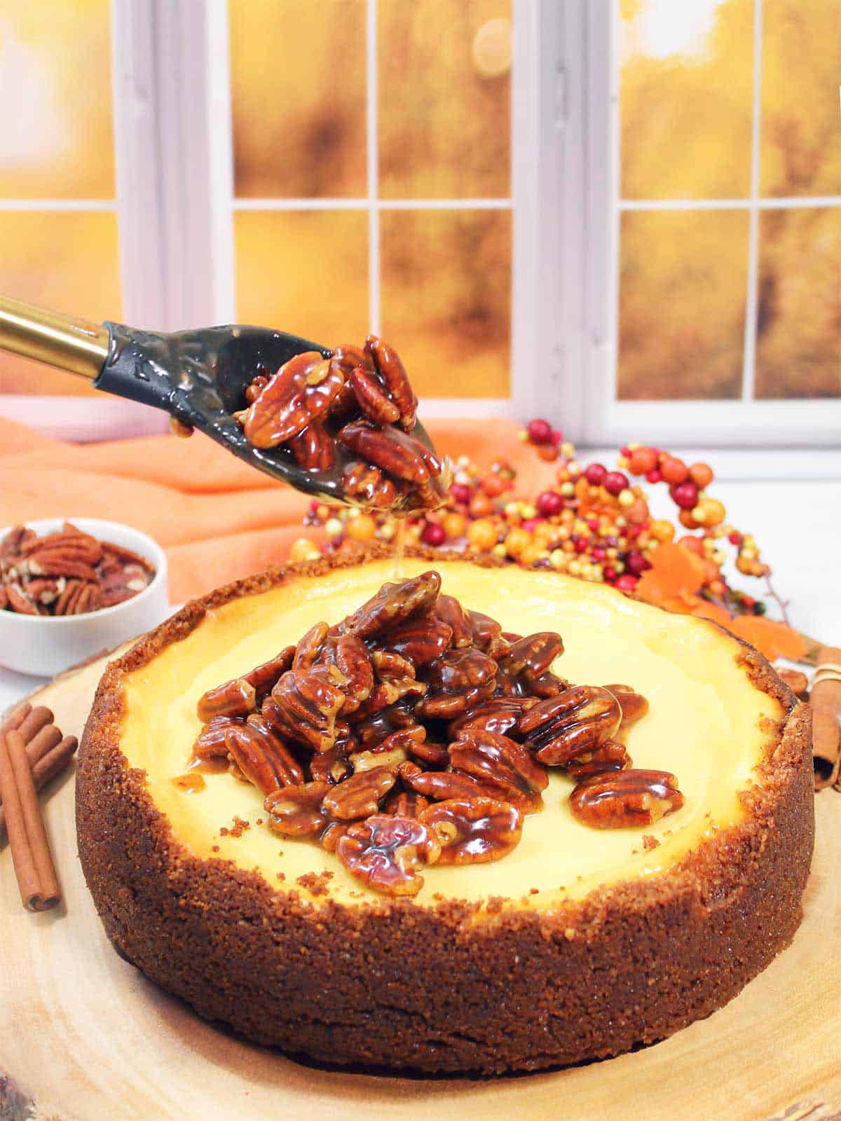 Spooning pecan pie topping on cheesecake.