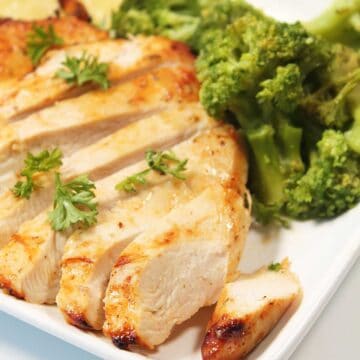 Sliced Air Fryer Chicken Breast on dinner plate with parsley garnish.
