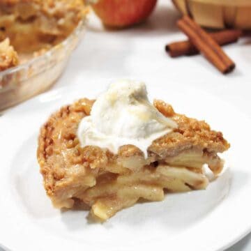 Slice of caramel apple pie with scoop of ice cream.