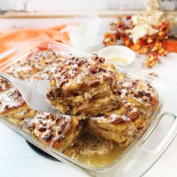 Lifting serving of cinnamon roll french toast out of casserole.