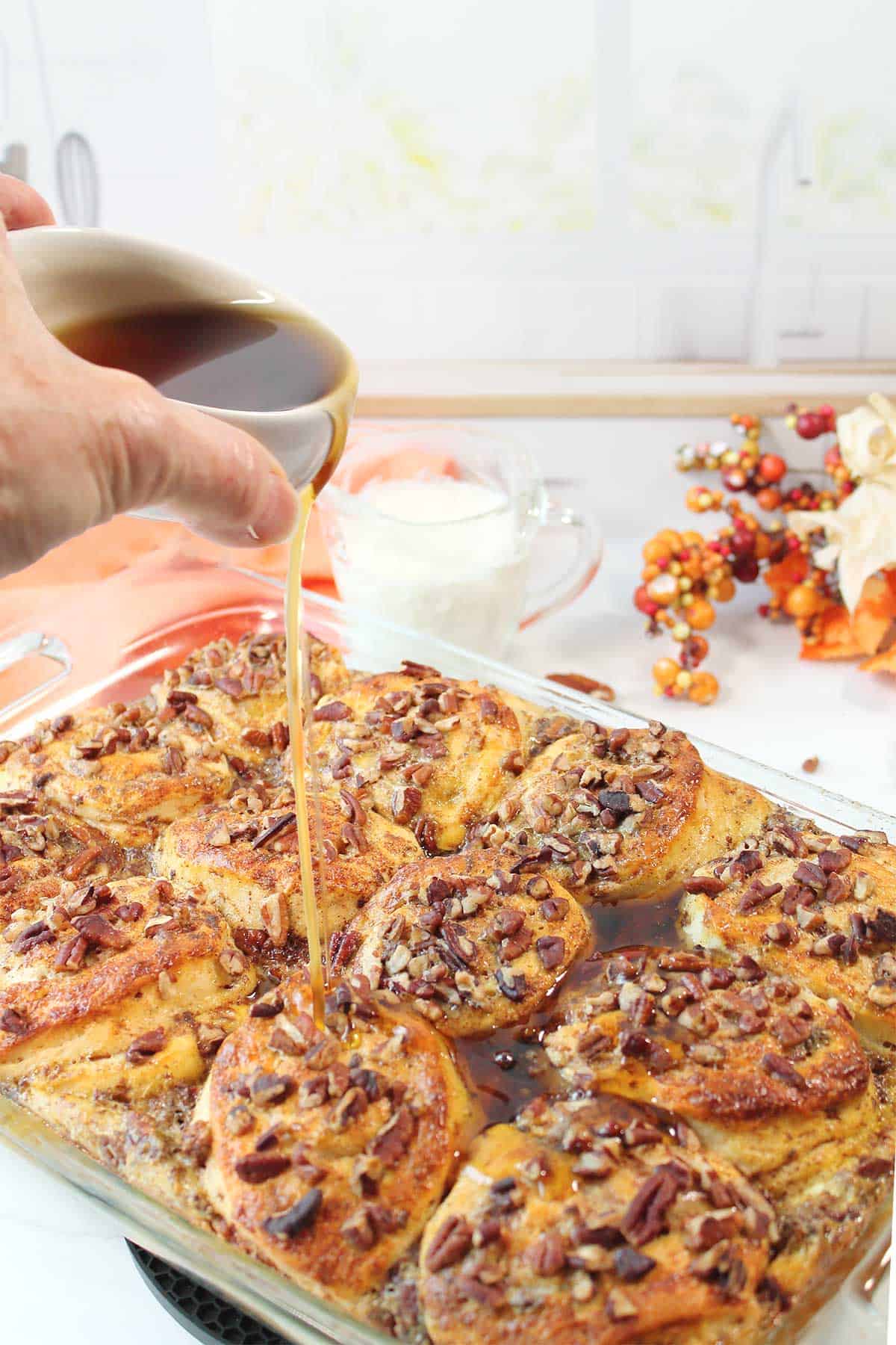 Drizzling maple syrup over baked cinnamon roll casserole.