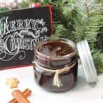 Closeup of jar filled with gingerbread simple syrup near Merry Christmas sign.