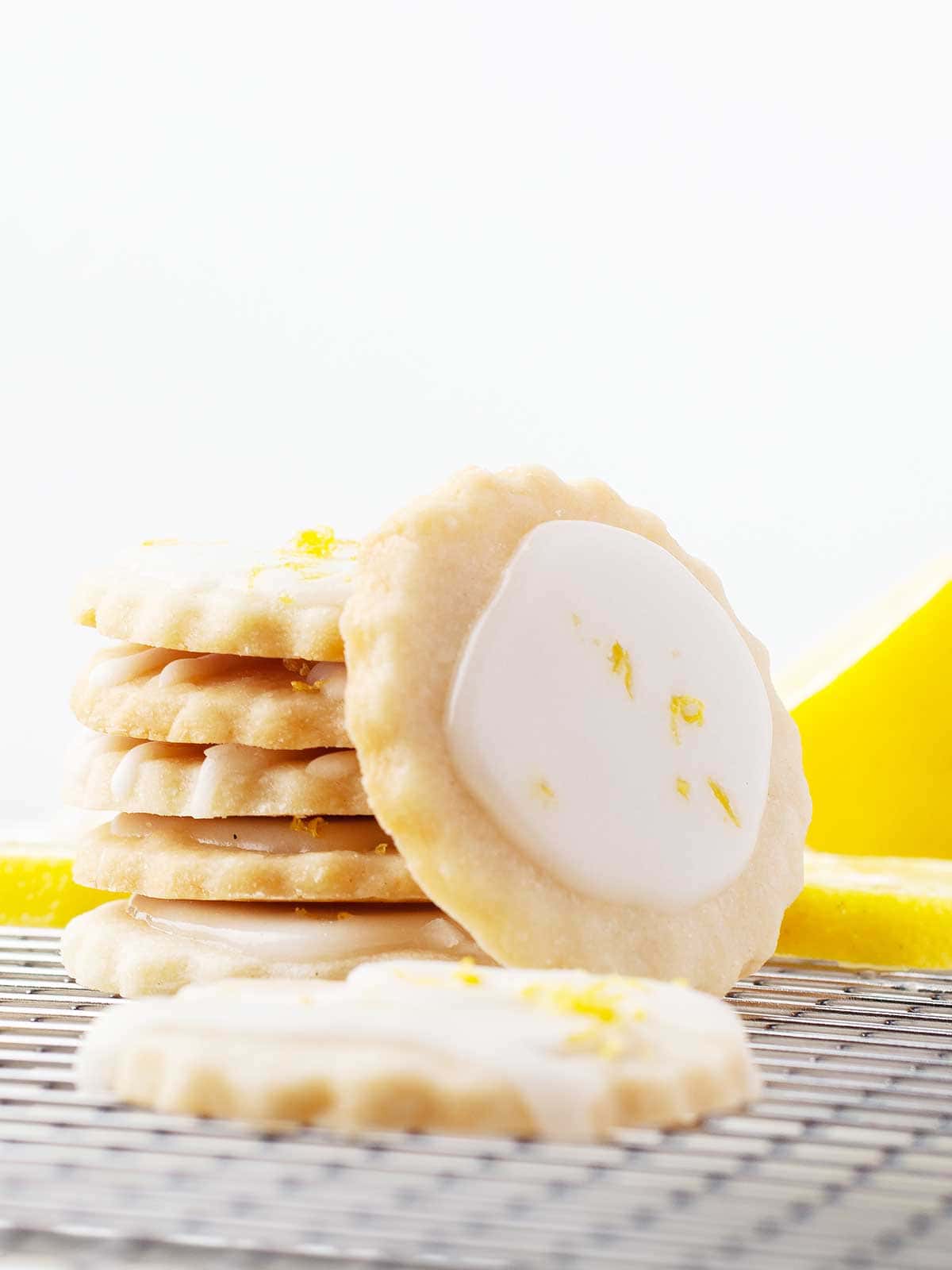 Stack of cookies with frosted shortbread cookie leaning on stack.