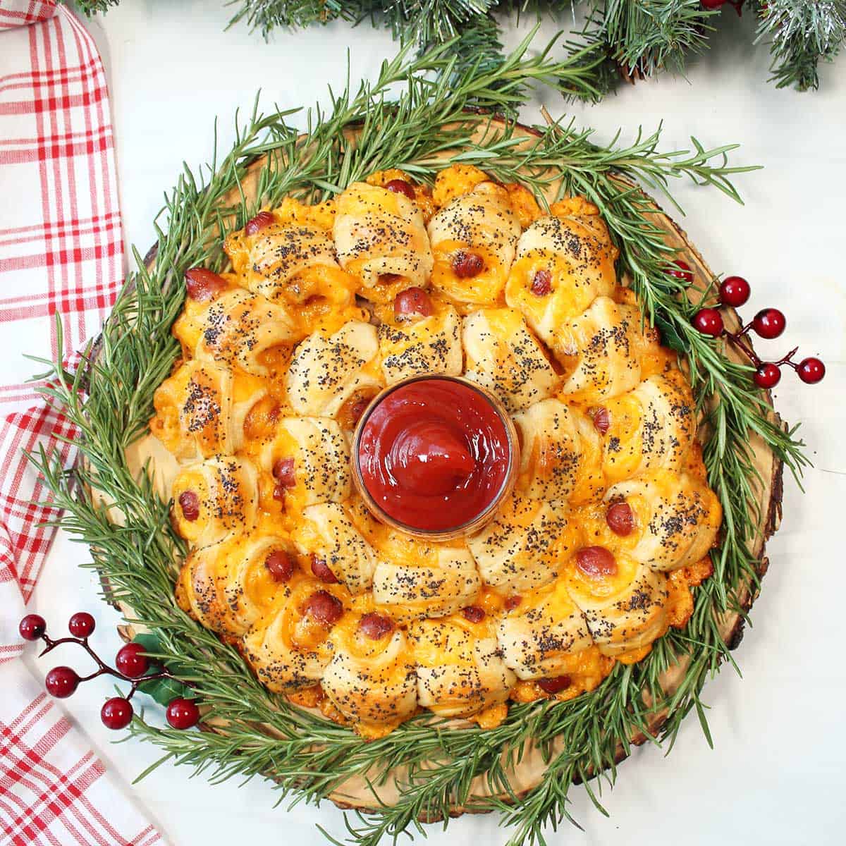 Overhead of pigs in a blanket wreath with ketchup in center.