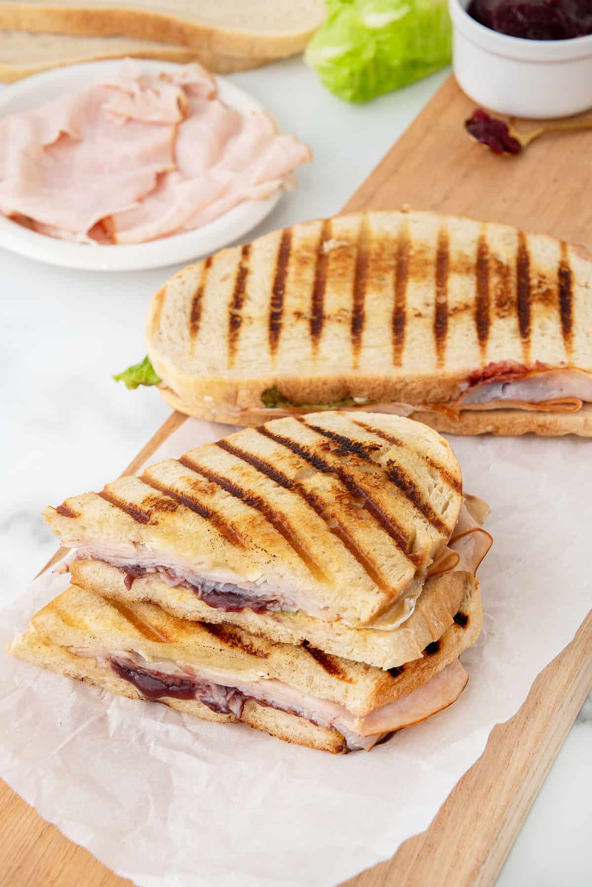 Turkey Cranberry Brie Paninis cut and uncut sandwich.