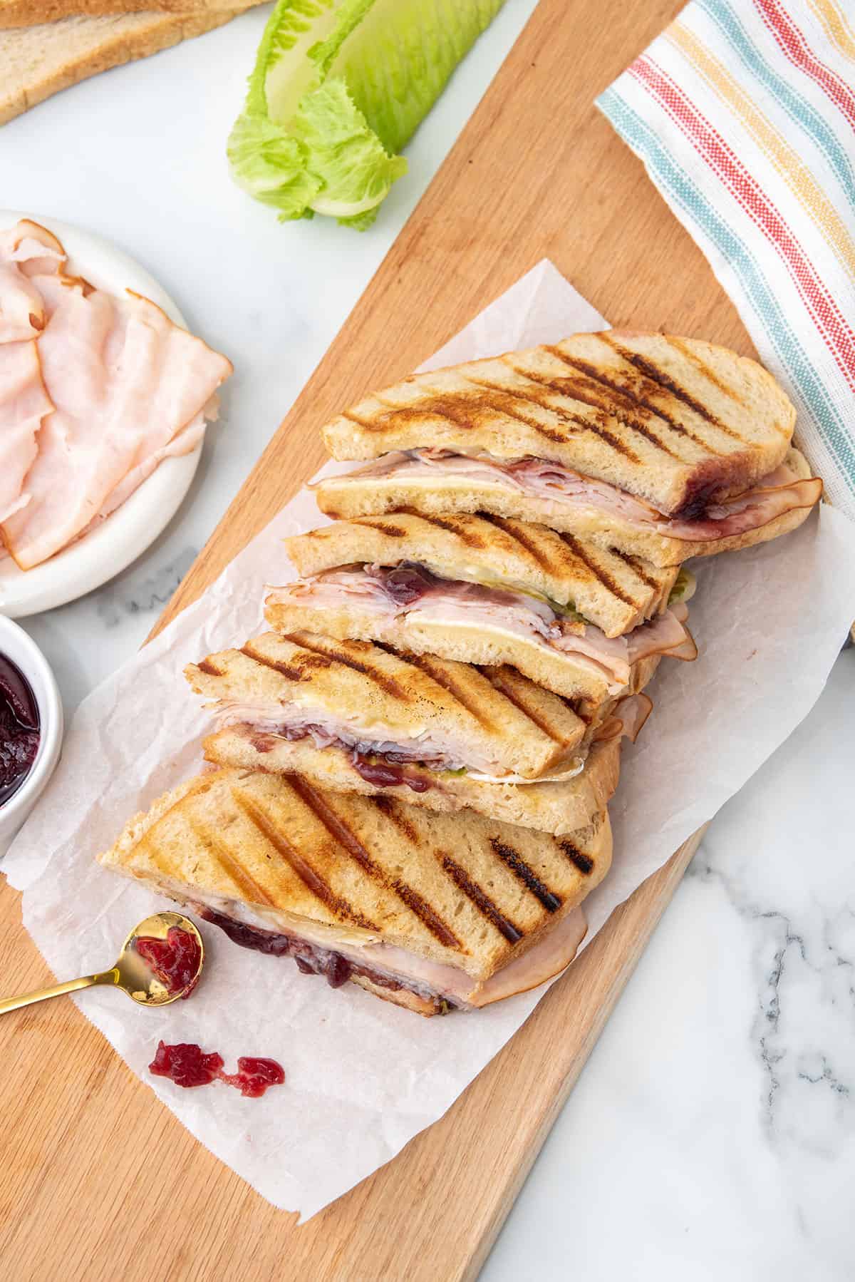 Turkey Cranberry Brie Panini fanned out on wooden board.