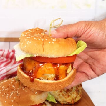 Holding burger with garnishes.