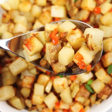 Closeup of home fries on serving spoon.